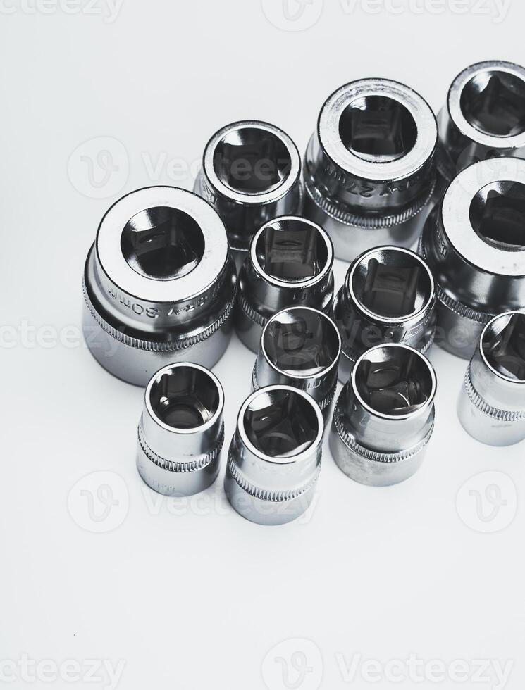 Selection of polished metallic socket wrenches arranged neatly on a white surface photo