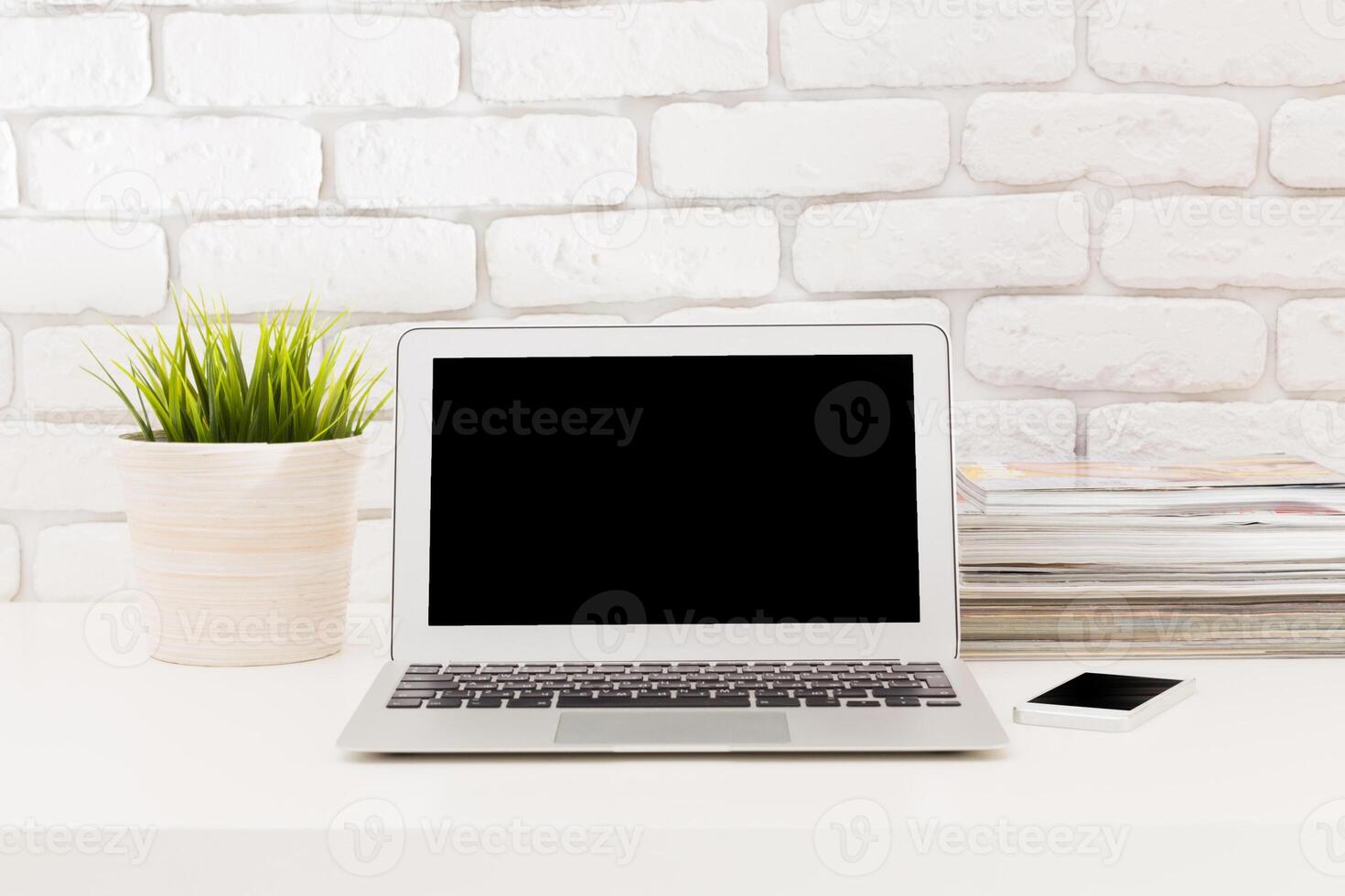 Modern workspace setup with a laptop, stationery, and plants arranged on a desk in a bright and inviting environment photo