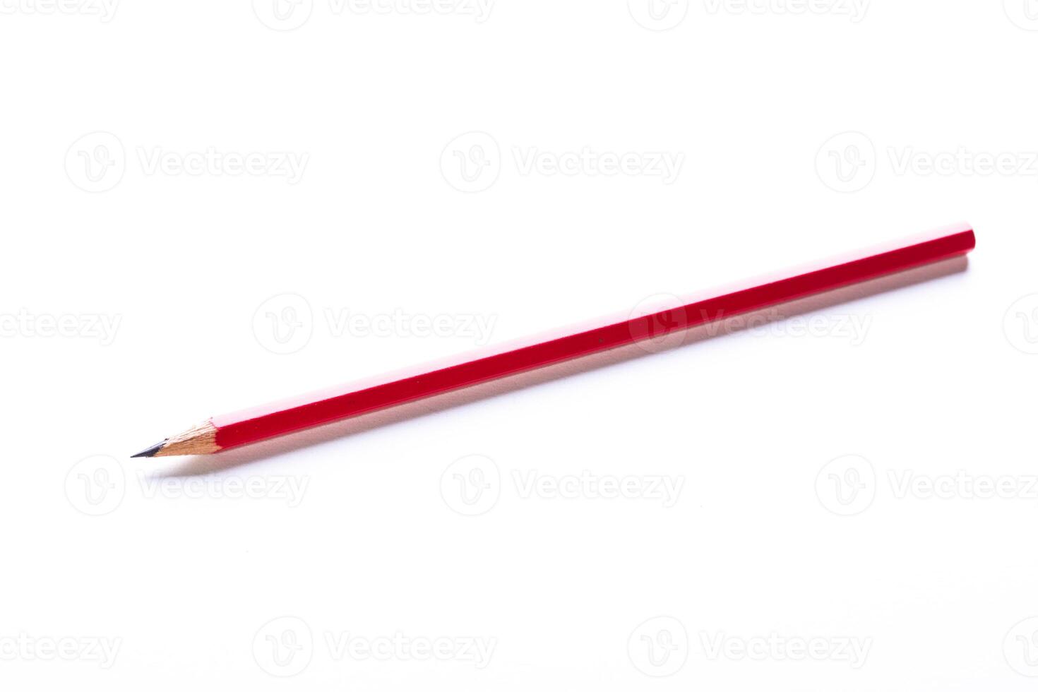 Red pencil resting on a white surface with a sharp tip and a smooth body ready for writing or drawing work photo