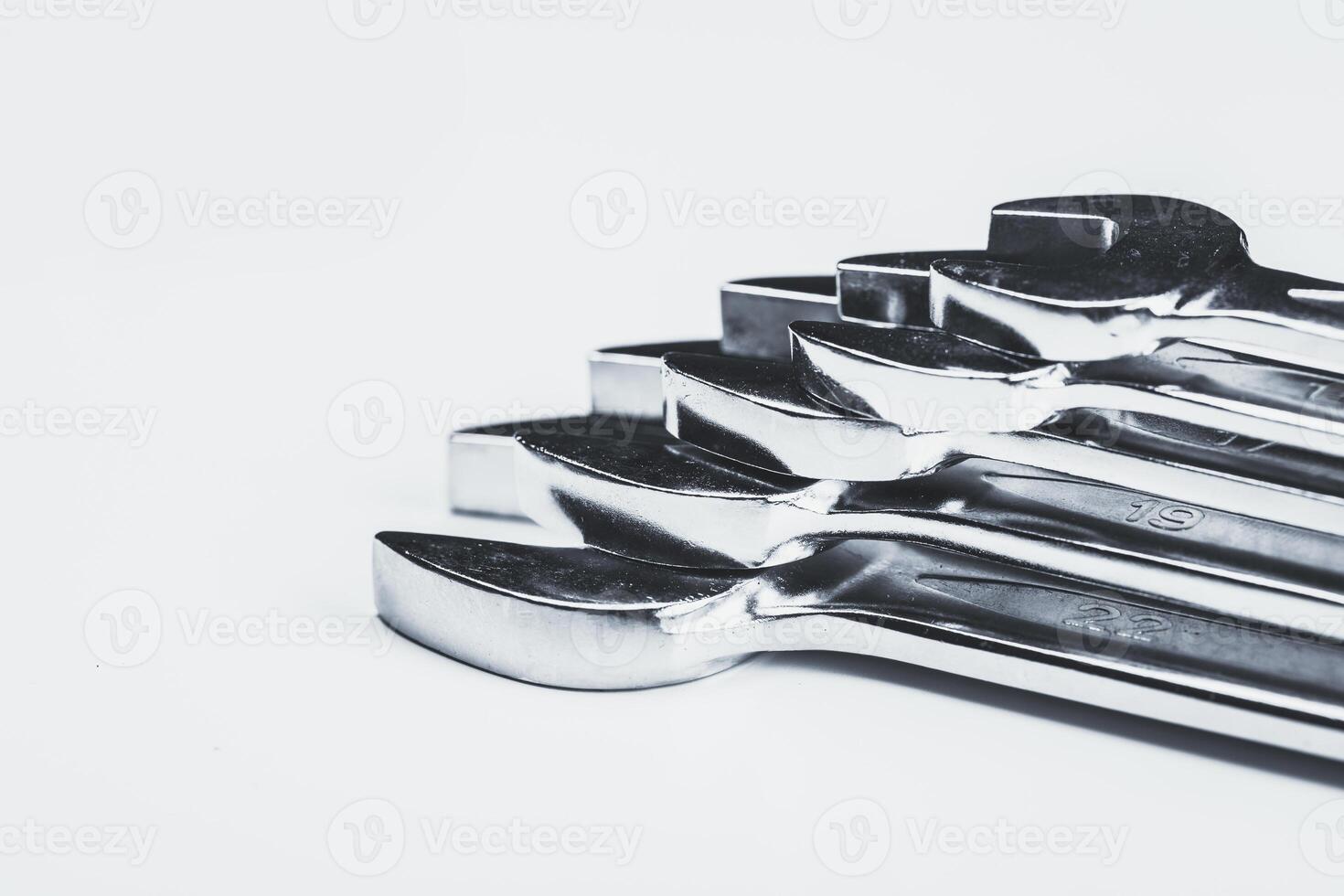 Wrenches lined up on a white surface showcasing their glossy metal finish and varied sizes ready for use photo