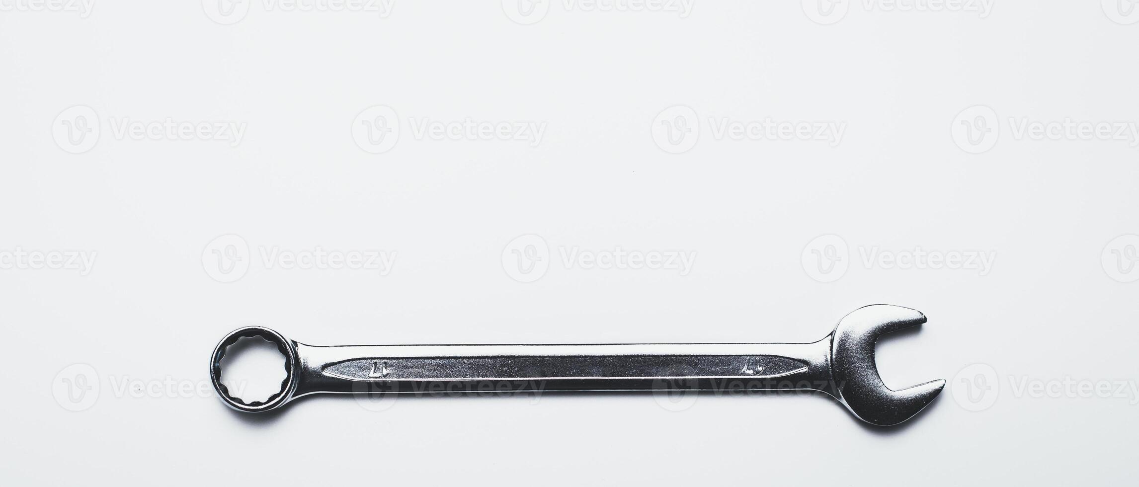 Metal wrench resting on a clean surface, ready for mechanical tasks and repairs in a workshop or garage setting photo