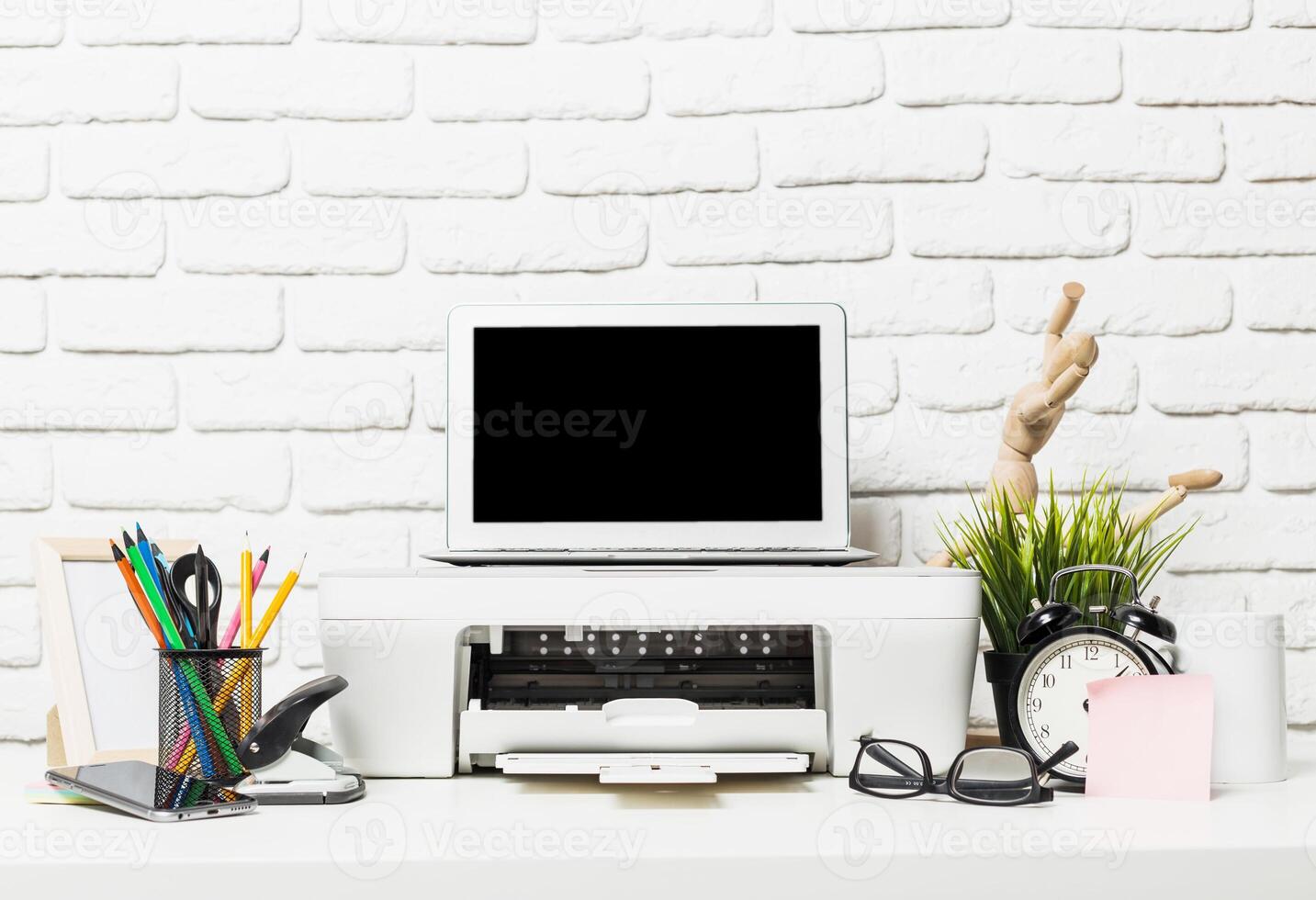 Creative workspace setup with printer, laptop, and various office supplies in a modern arrangement photo