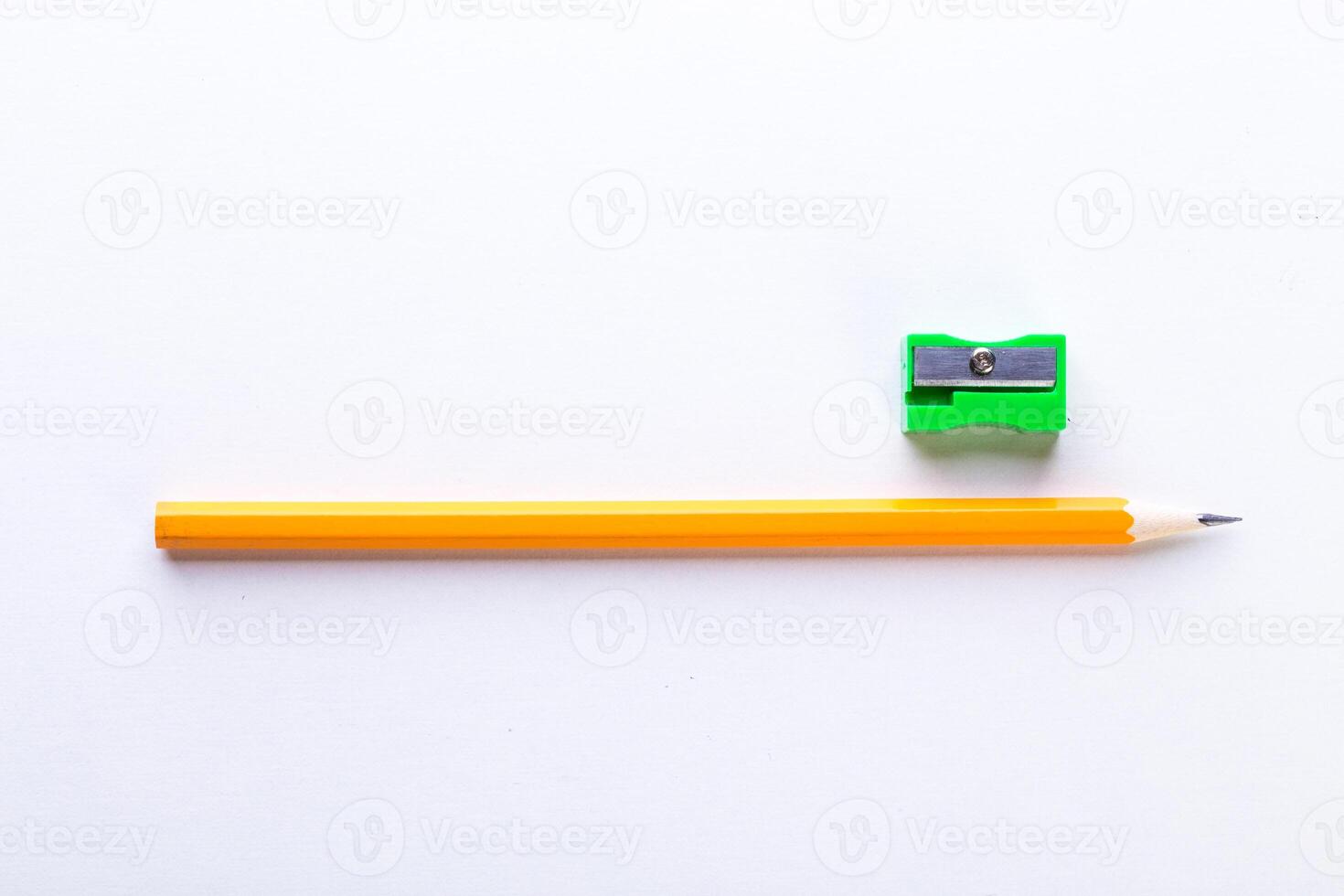 Bright yellow pencil and green sharpener arranged on a clean white surface photo