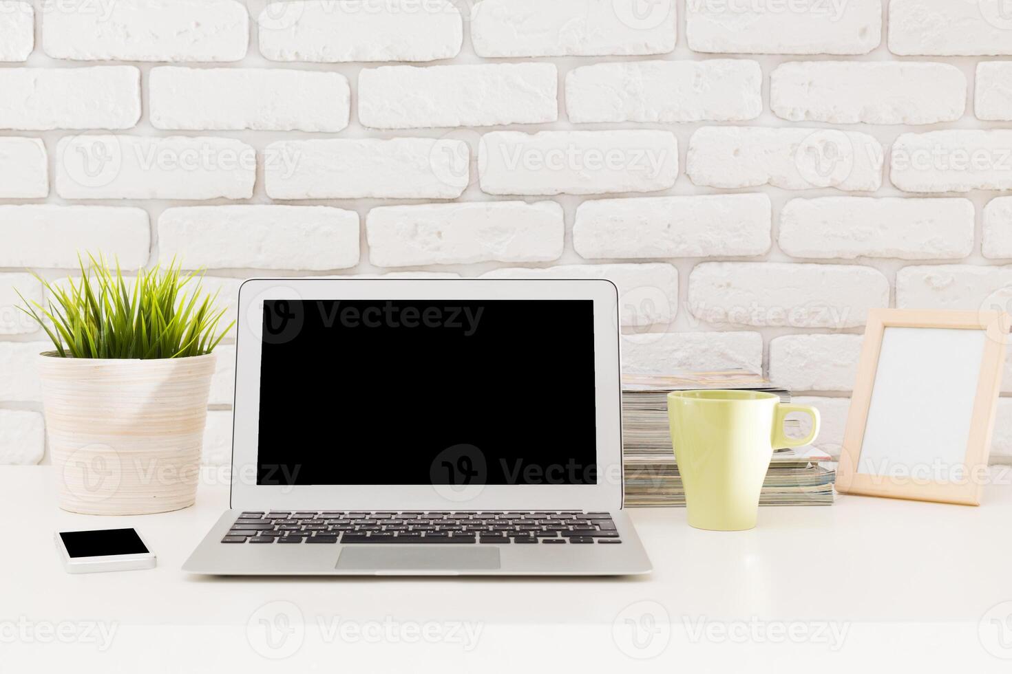 Modern workspace setup with a laptop, stationery, and plants arranged on a desk in a bright and inviting environment photo