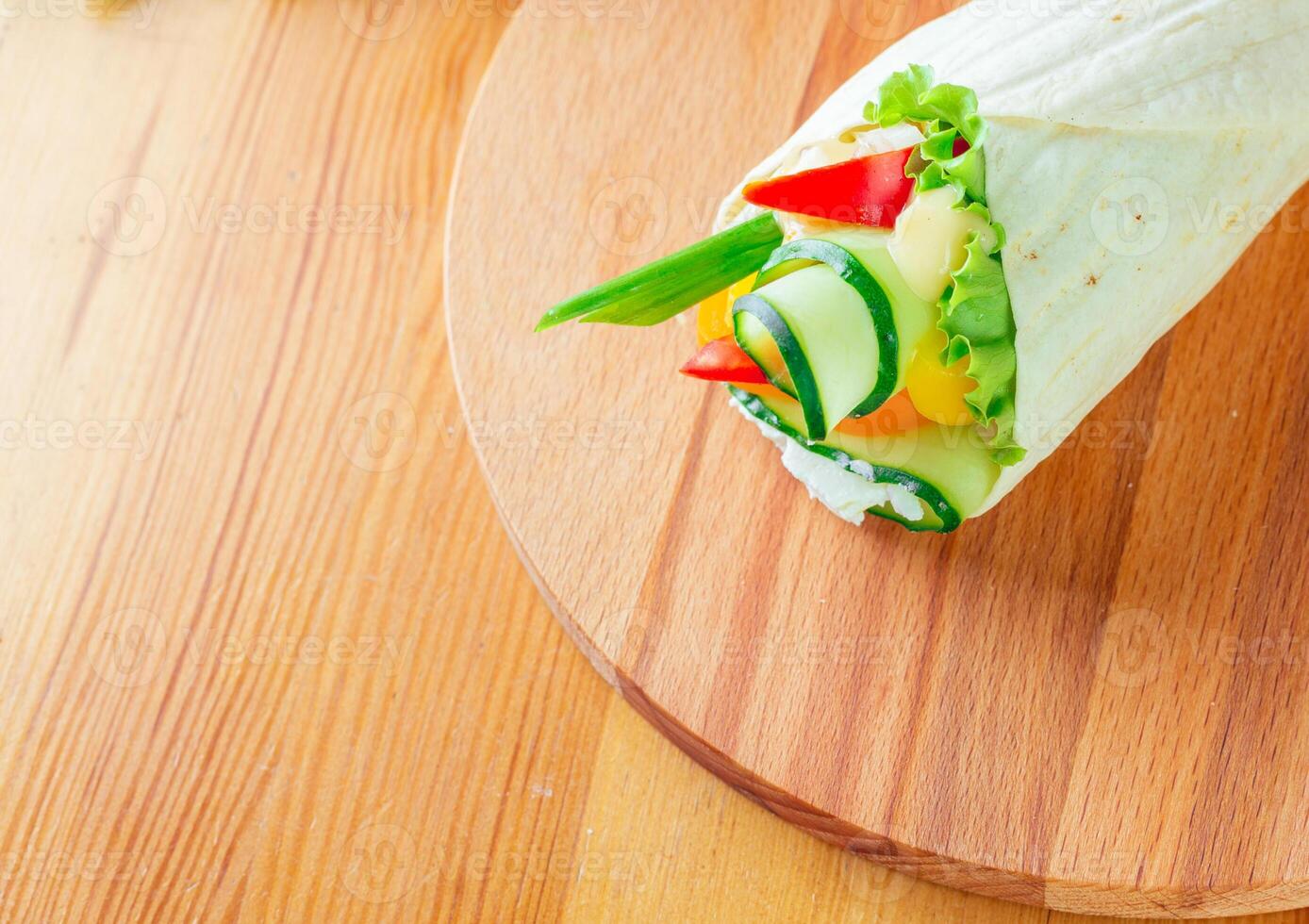 Fresh vegetable wrap presented on a wooden board in a bright kitchen setting photo