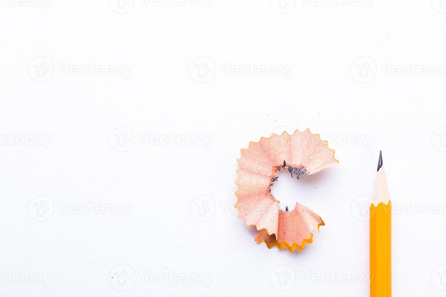 Pencil shavings and a sharpened yellow pencil on a clean white surface during a creative session photo