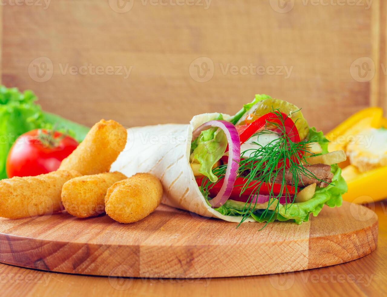 Delicious burrito wrap served with crispy snacks on a wooden board in a bright kitchen setting photo