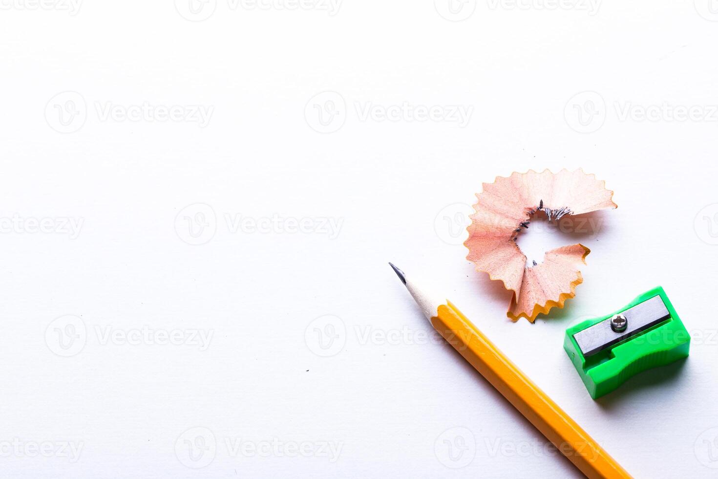 Pencil, sharpener, and shavings on white background create a simple workspace scene photo