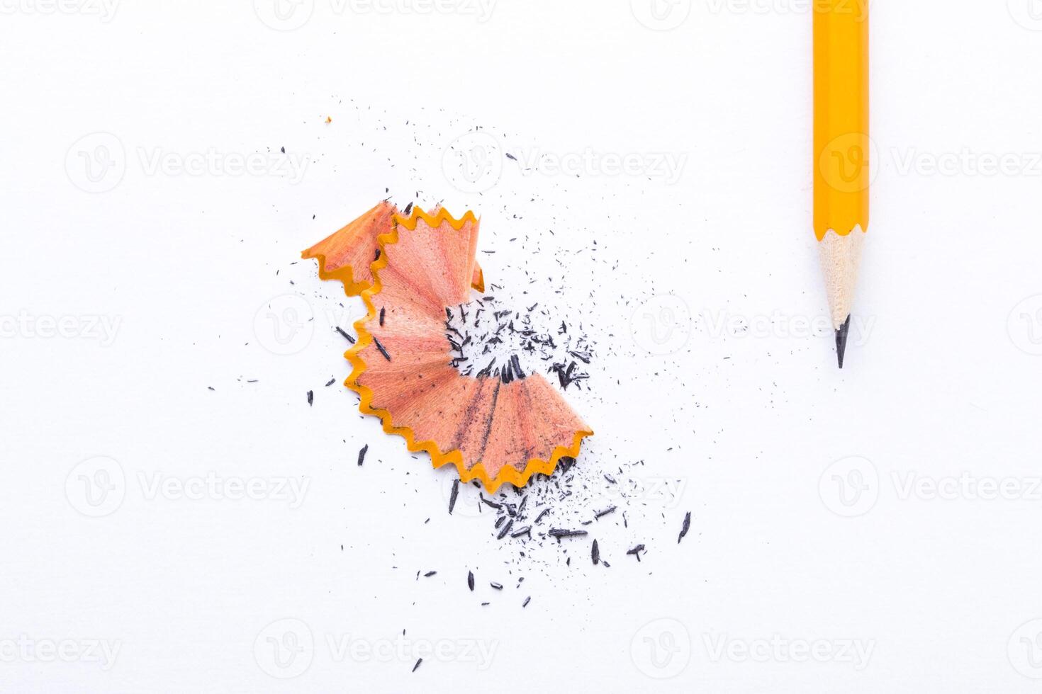 Sharpened pencil next to orange pencil shavings on white background in a creative workspace photo