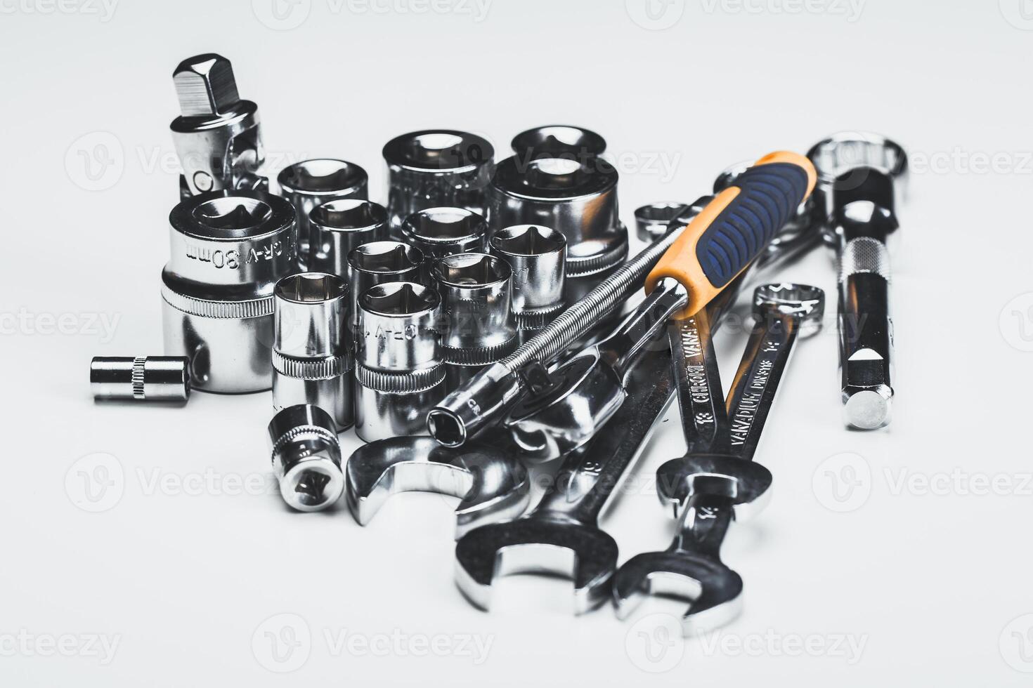 Collection of various hand tools including sockets, wrenches, and a ratchet set on a white surface for automotive repairs photo