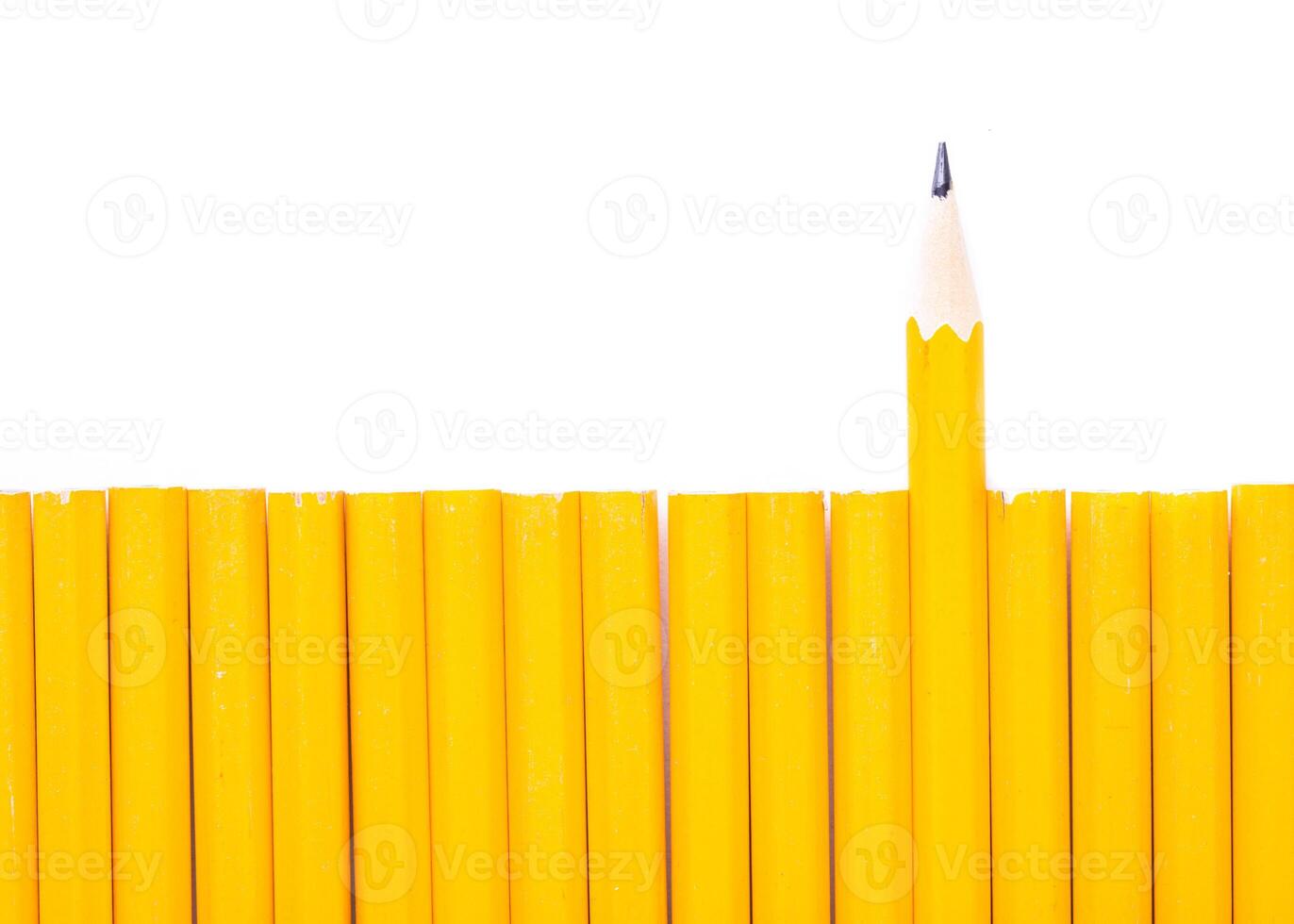 Unique arrangement of yellow pencils with one sharpened pencil standing out from the group on a white background photo