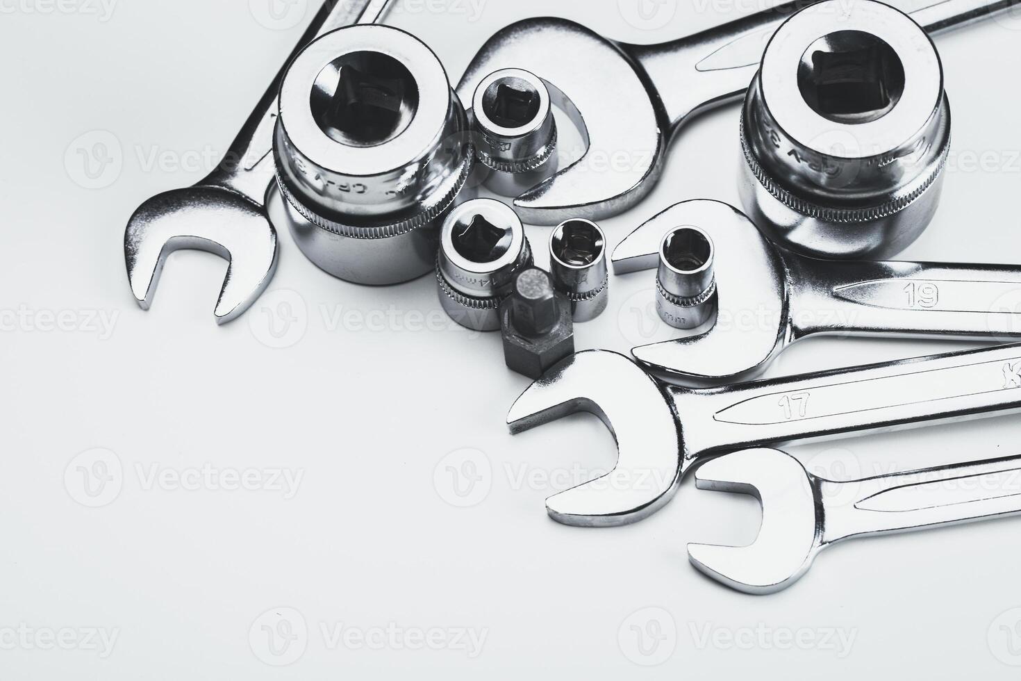 Various metal tools arranged neatly on a light surface in a workshop setting for repair tasks photo