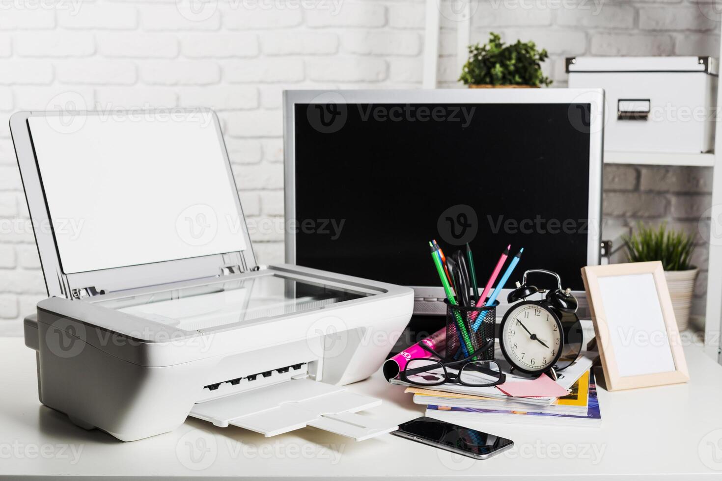 Desk clutter with printer, computer, and office supplies in a bright workspace setting photo