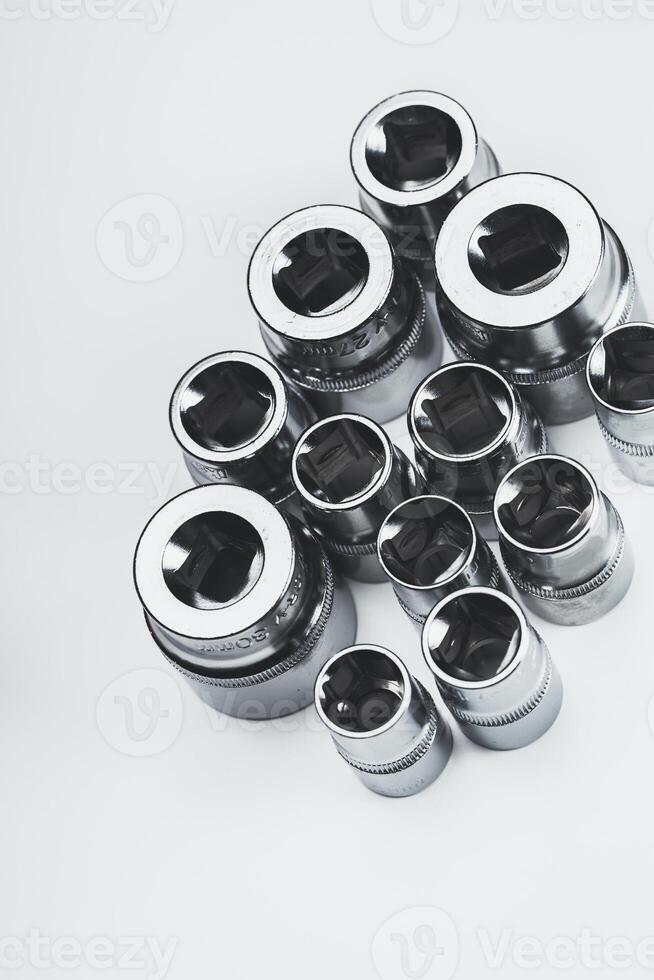 Various sizes of chrome socket wrenches arranged on a plain surface in a well-lit workspace photo