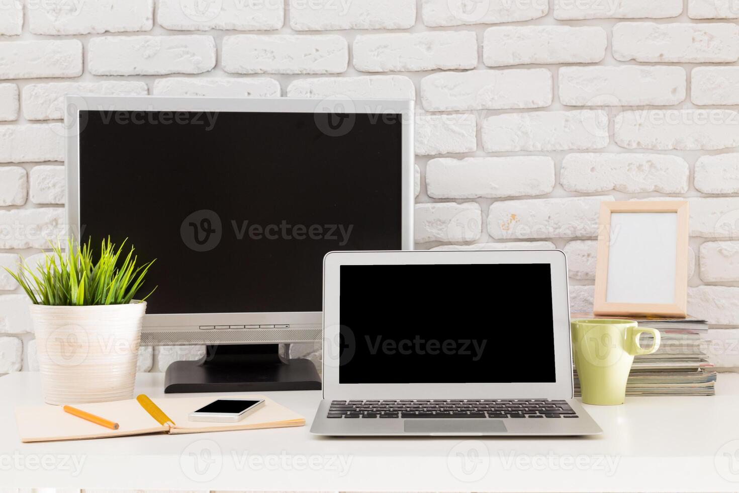 Modern workspace featuring a laptop, desktop monitor, and decorative elements in a minimalistic setting photo