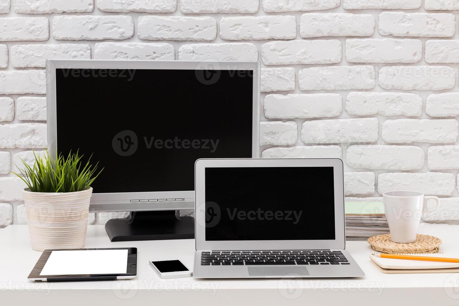 Modern workspace setup with a laptop, stationery, and plants arranged on a desk in a bright and inviting environment photo