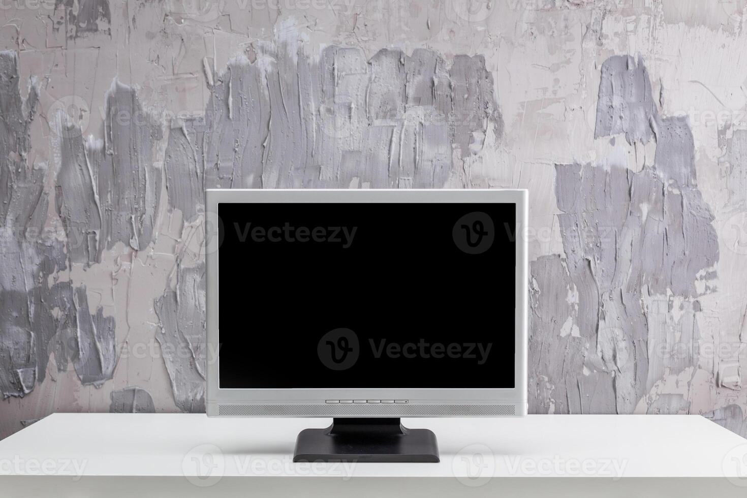 Modern minimalistic workspace featuring a blank computer monitor against a textured gray wall photo