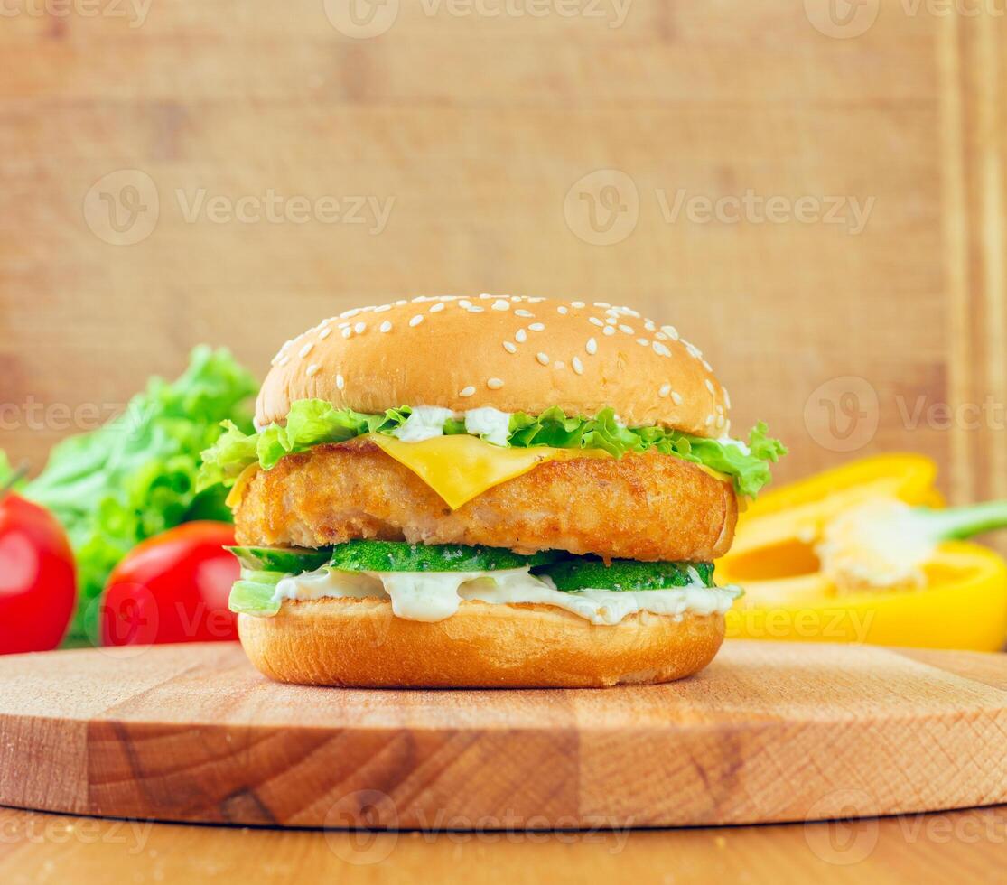 Delicious chicken sandwich with fresh vegetables on a wooden cutting board in a bright kitchen setting photo
