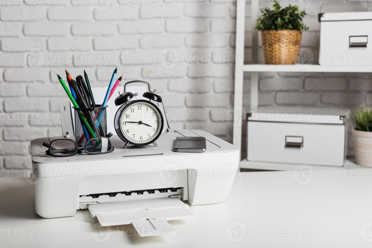 Organizing a home office workspace with a printer, clock, and stationery at a well-lit area photo