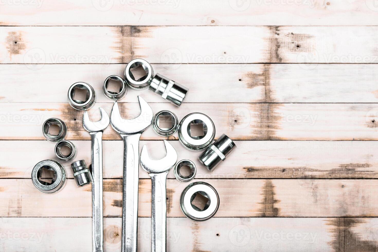 Tools arranged on a wooden surface showcase various sizes of wrenches and sockets used for mechanical work photo