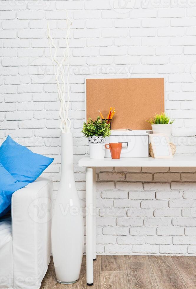 Cozy home workspace with a white desk, decorative plants, and a comfortable sofa in a bright setting photo