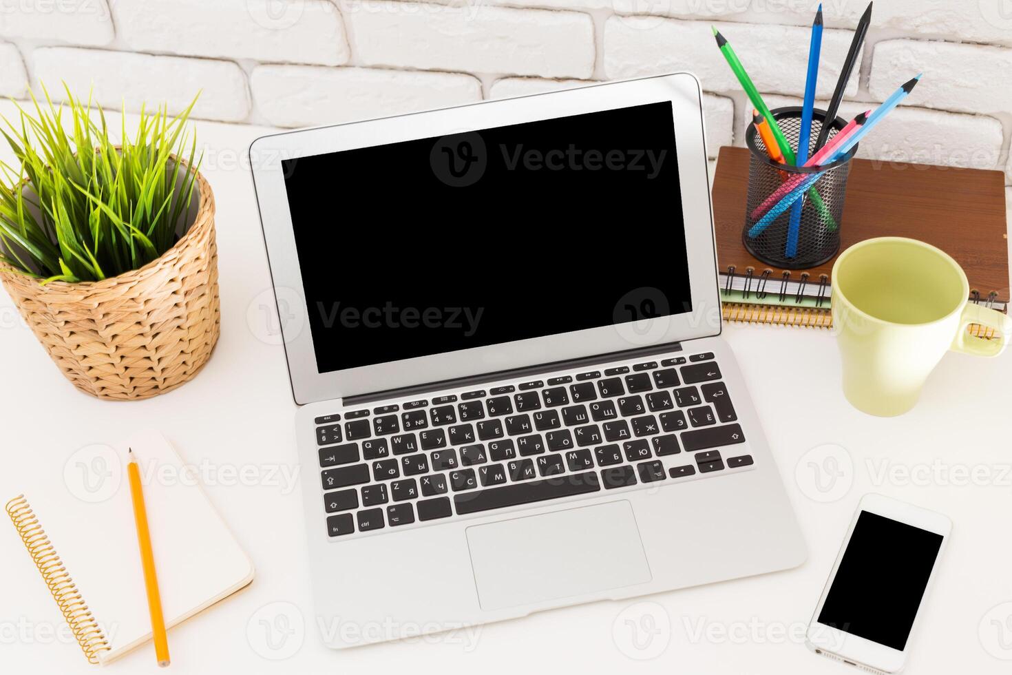 Workstation setup with laptop, stationery, and plants for a productive environment during the day photo