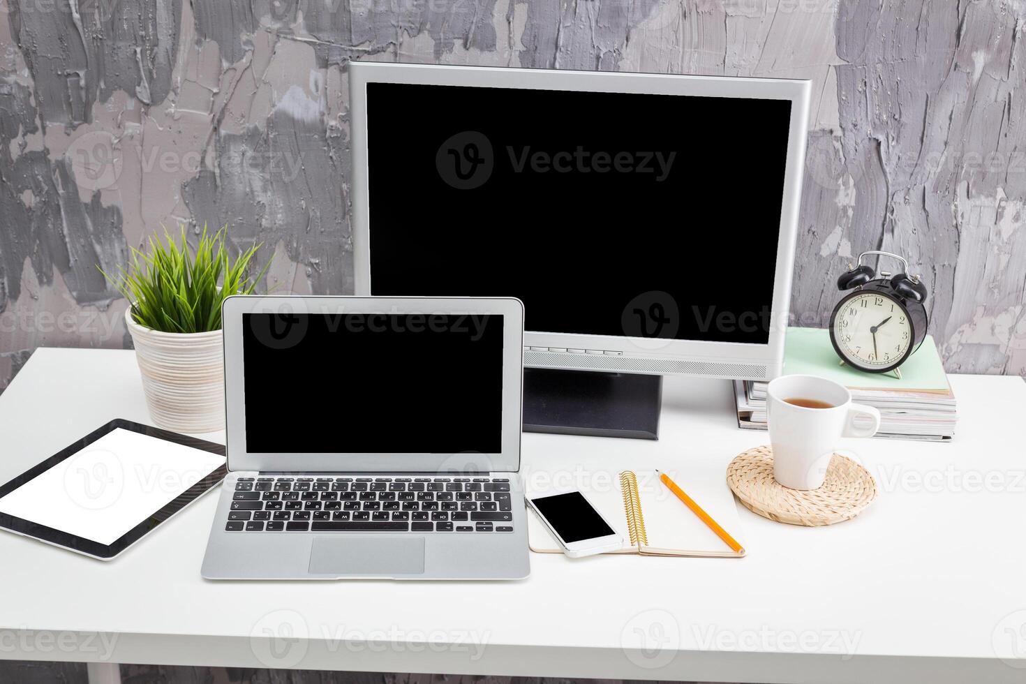 Home office setup with laptop, monitor, and coffee cup on a white desk during daylight photo