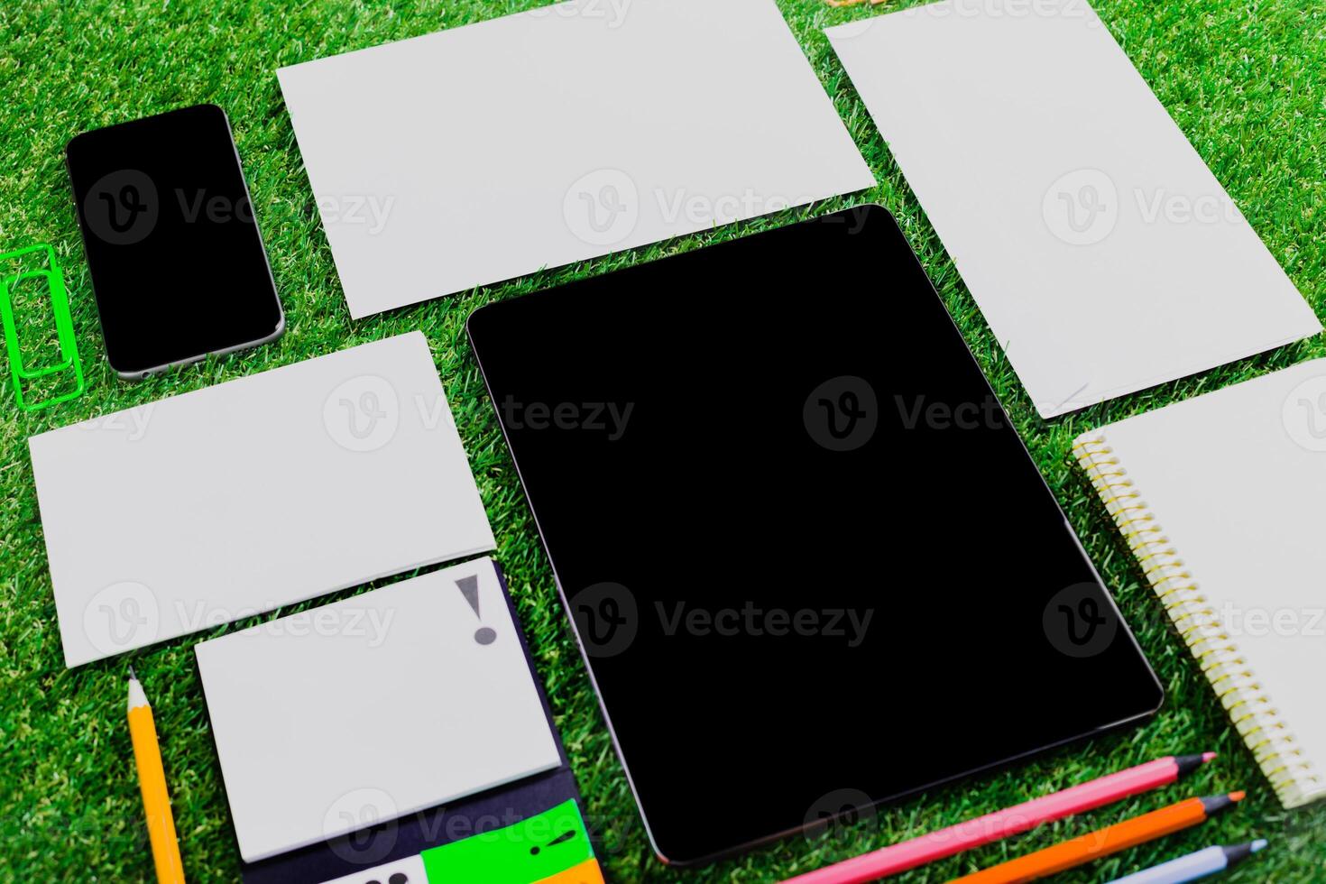 Desk setup on green grass with digital and stationary tools for creative work during daytime photo