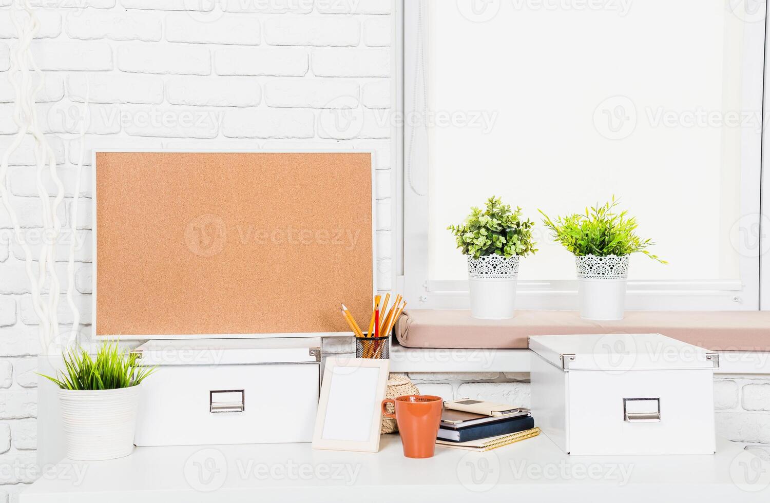Minimalist workspace with corkboard, potted plants, and organized stationery during daylight hours photo