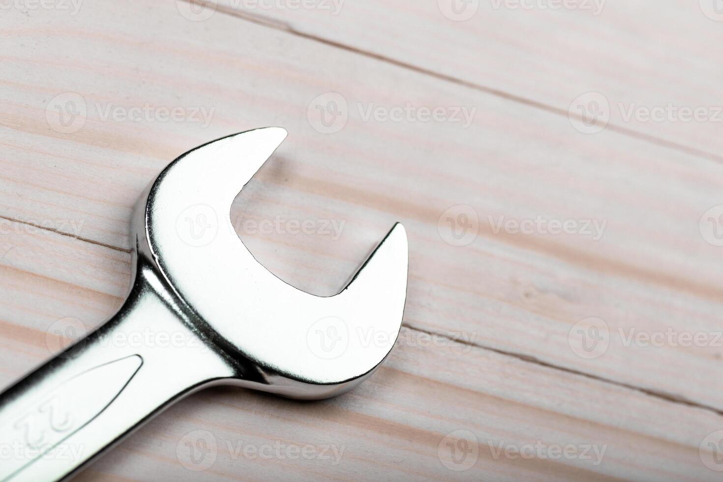 Close-up view of a shiny wrench resting on a wooden surface in a workshop setting during daylight hours photo