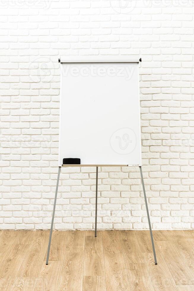 Flip chart set up against a white brick wall in a well-lit indoor space for a business meeting or presentation photo