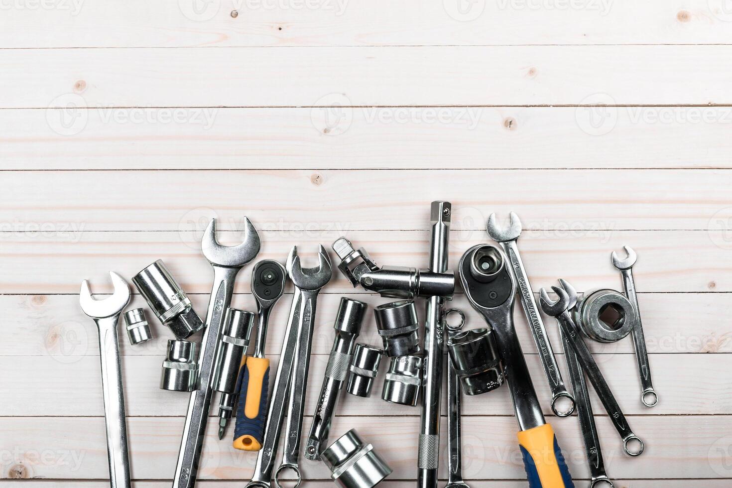 Collection of various metal hand tools arranged on a light wooden surface for home repair and maintenance tasks photo