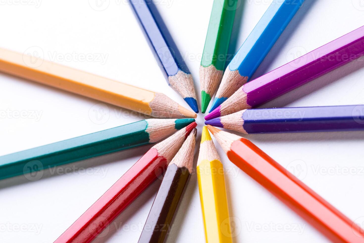 Colorful pencils arranged in a circular pattern on a white surface for creative artwork photo