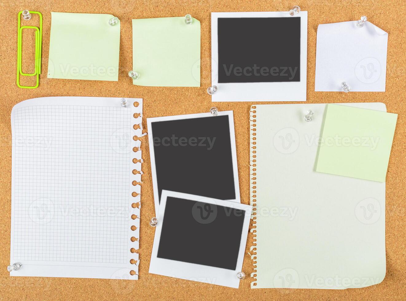 Collection of blank sticky notes and empty photo frames on a corkboard background for organization