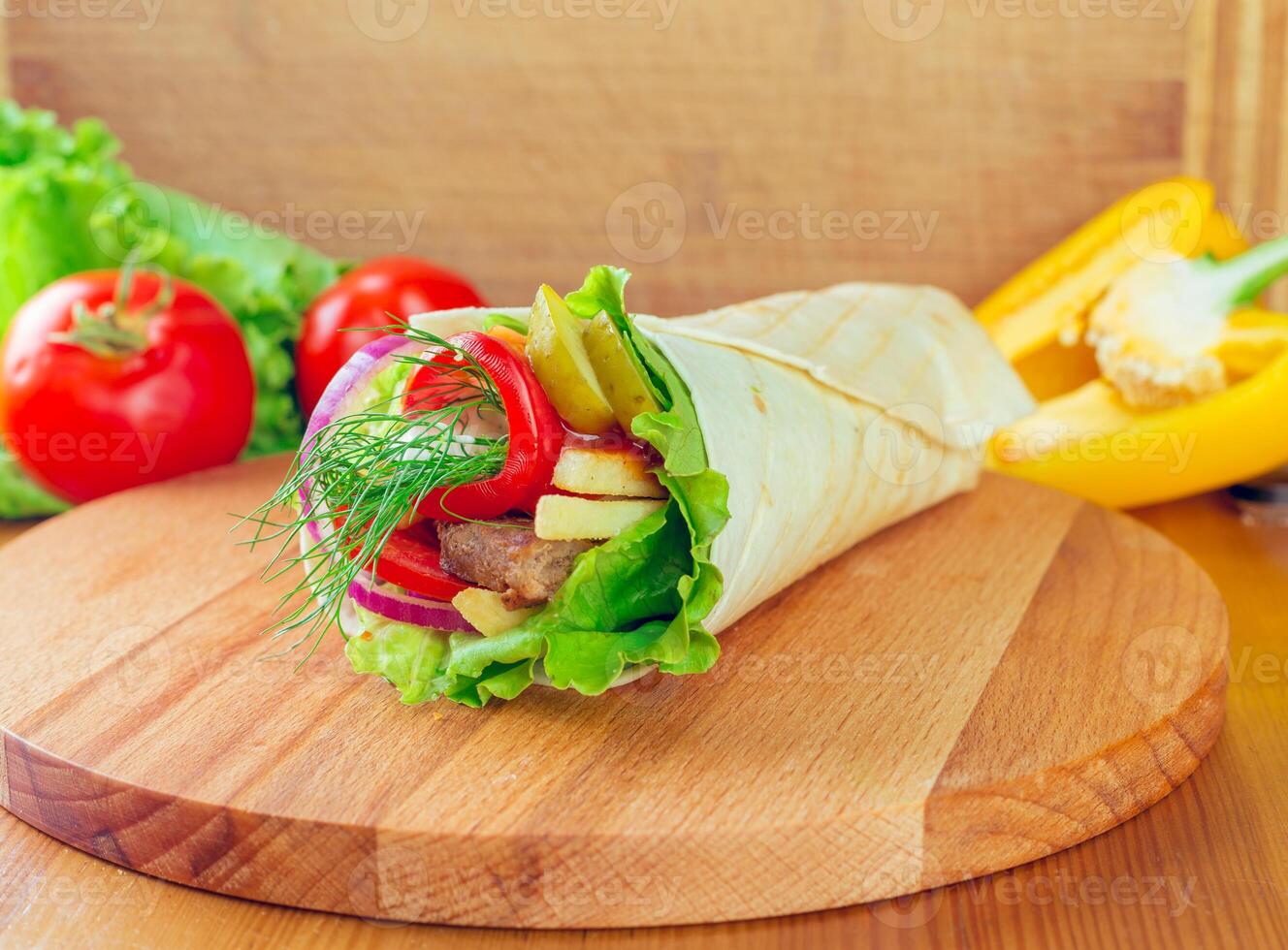Fresh wrap filled with vegetables and meat on a wooden cutting board in a kitchen photo