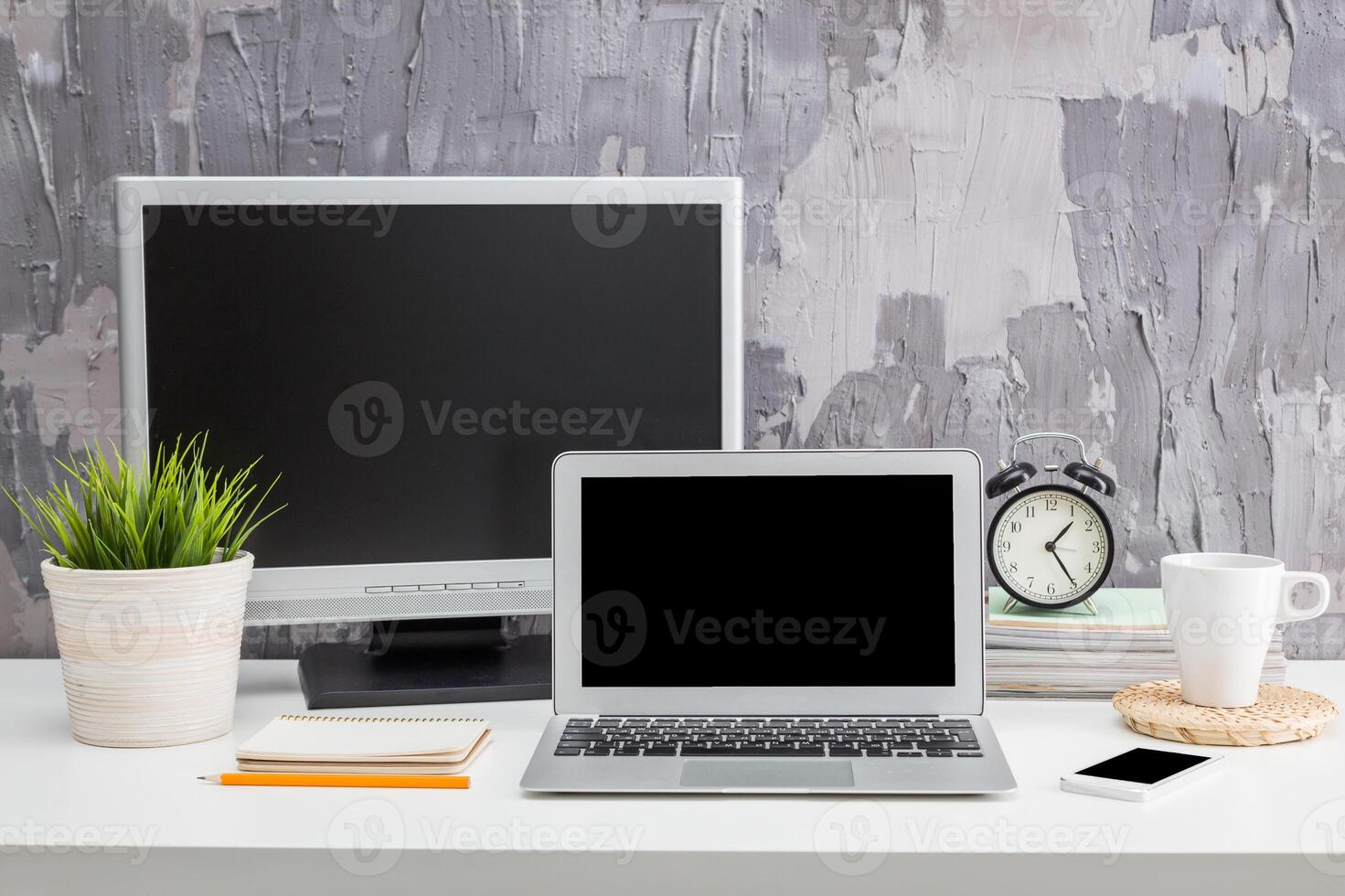 Minimalistic workspace with laptop, monitor, clock, and plants for a productive environment photo