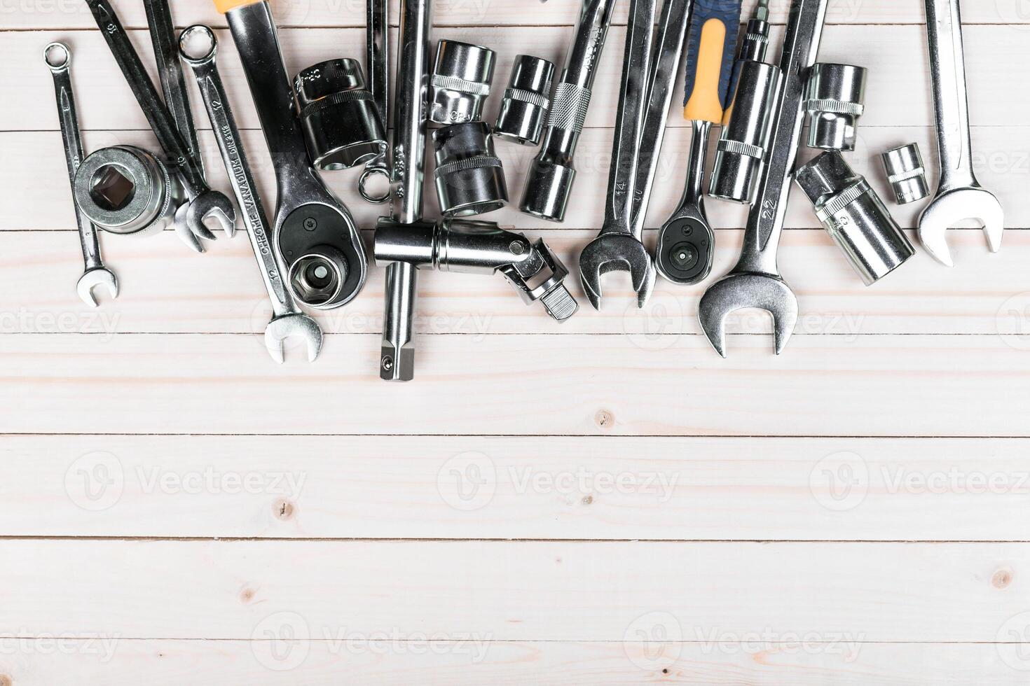 Collection of metal tools arranged on a wooden surface ready for automotive or mechanical work photo