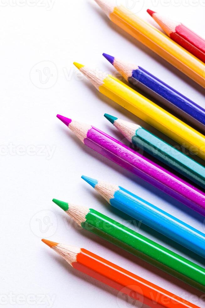 Vibrantly colored pencils lined up on a clean white surface ideal for creative artwork and drawing sessions photo