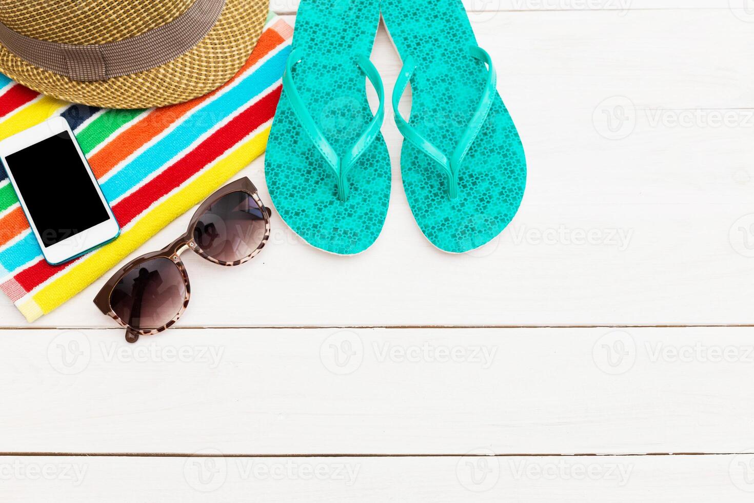 Bright summer essentials on a beach mat with flip flops, sunglasses, and a smartphone ready for relaxation photo