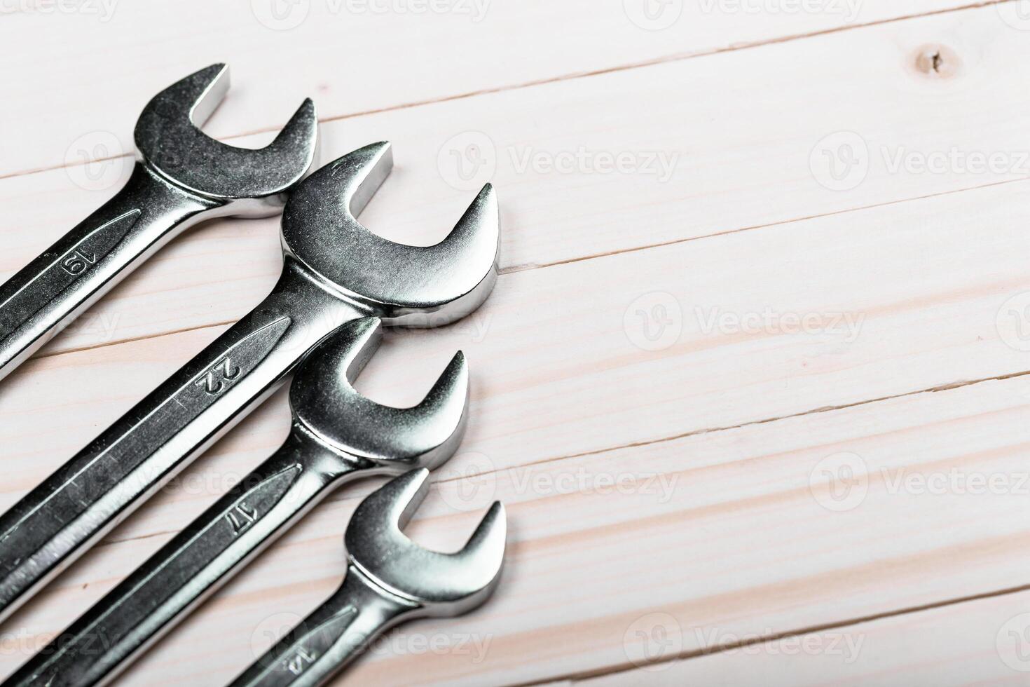 Various sizes of wrenches arranged on a wooden surface for toolbox organization in a workshop setting photo