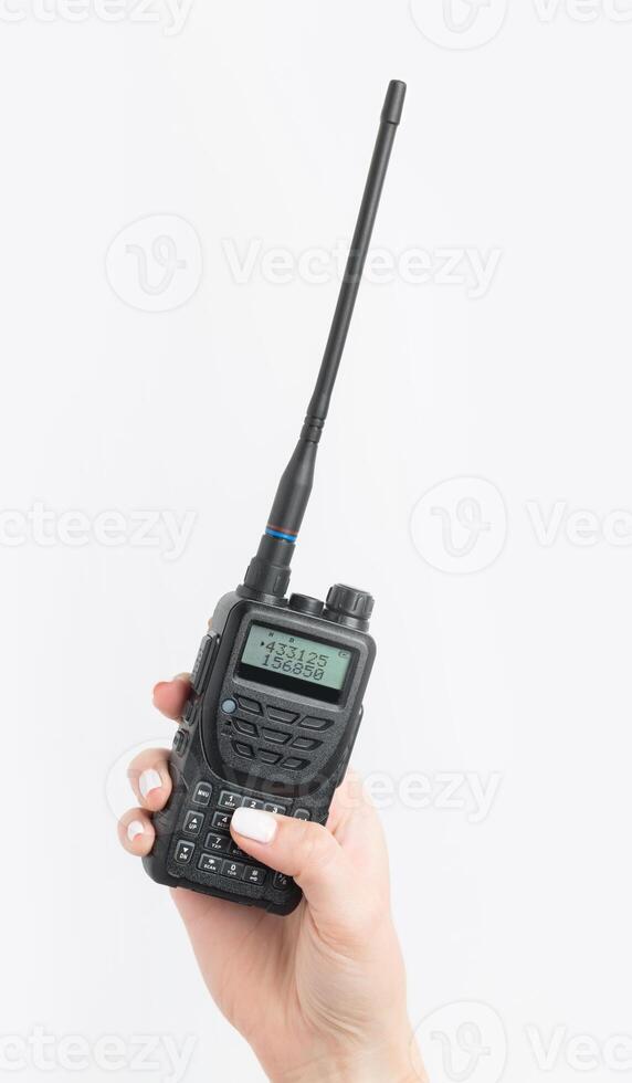Handheld radio device held in a hand with a visible screen and antenna for communication in outdoor activities photo