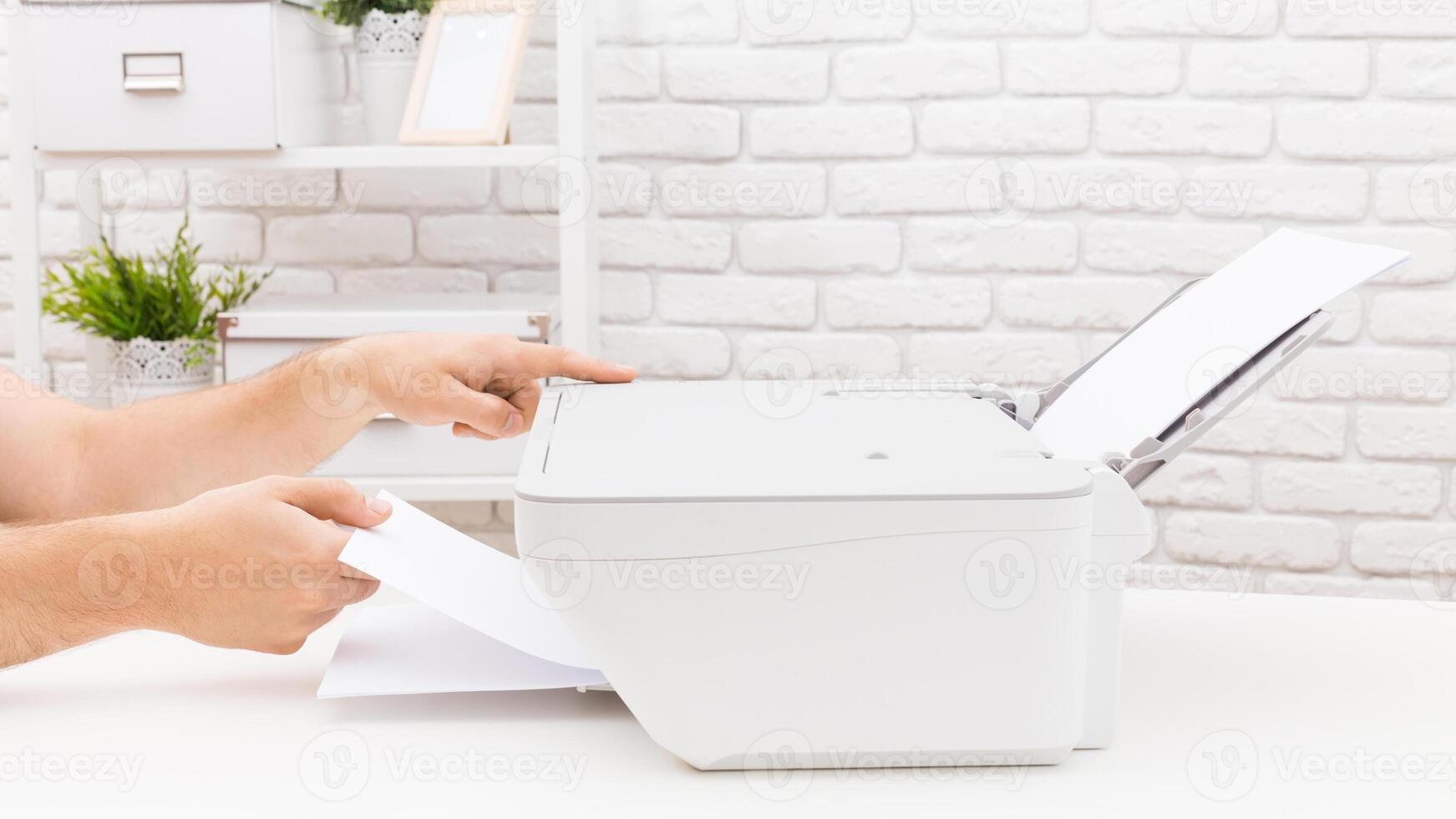 Person preparing documents for printing in a bright office setting with white brick walls and shelves of plants photo