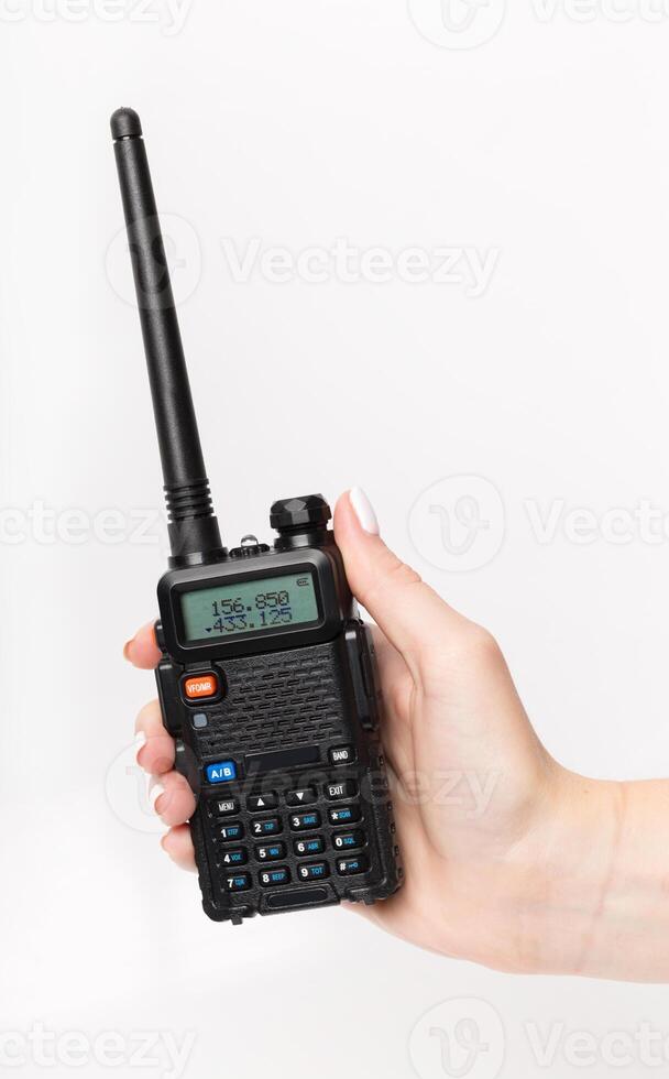 Handheld radio communicator held by a person with a visible display and antenna in a neutral setting photo