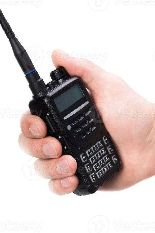Handheld communication device held in a person's hand with a focused grip on the controls and antenna during a busy outdoor scenario photo
