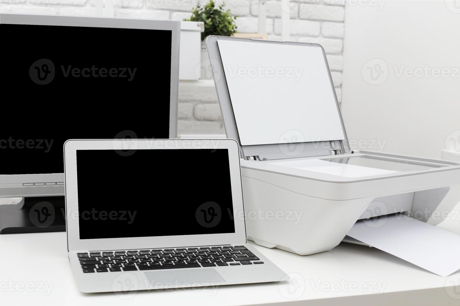 Home office setup with laptop printer and monitor in a modern workspace during daylight hours photo