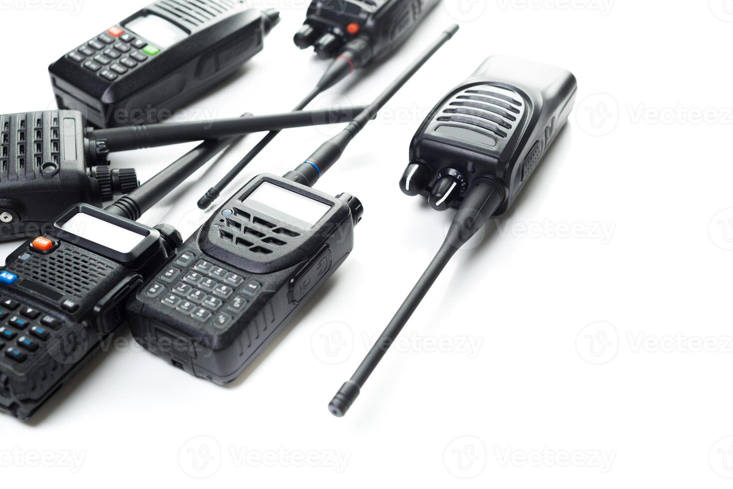 Communication devices arranged on a white surface with multiple two-way radios and antennas photo