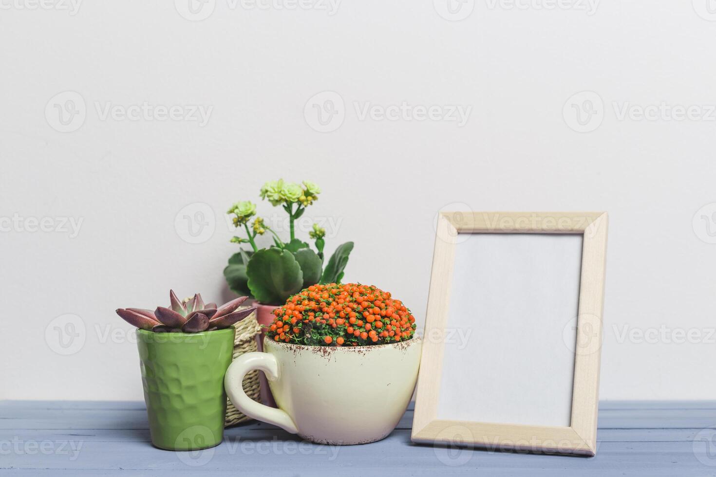 Colorful flower arrangement and an empty frame on a wooden table in a bright setting photo