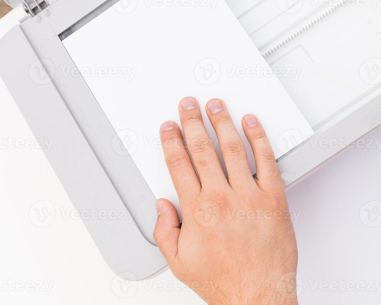 Hand placing paper into a scanner for digital documentation in a bright office setting during daytime hours photo