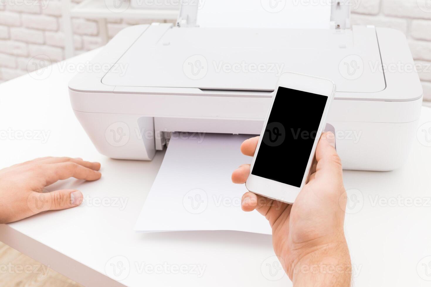 Using a smartphone to print documents from a printer in a modern workspace during bright daylight photo