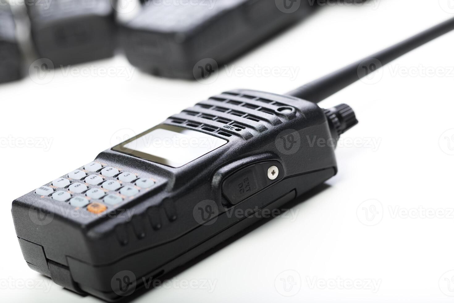 Modern two-way radio on a white surface with additional radios blurred in the background for communication use photo